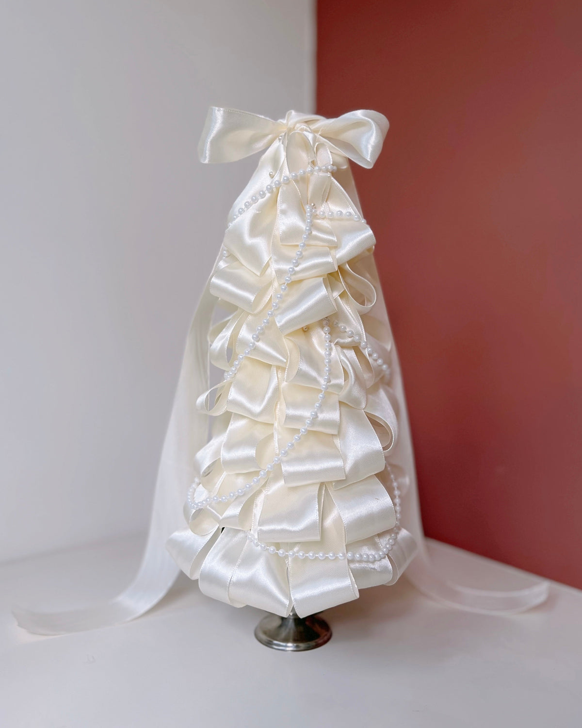 Dried tabletop Christmas tree with white satin ribbons and pearl strings