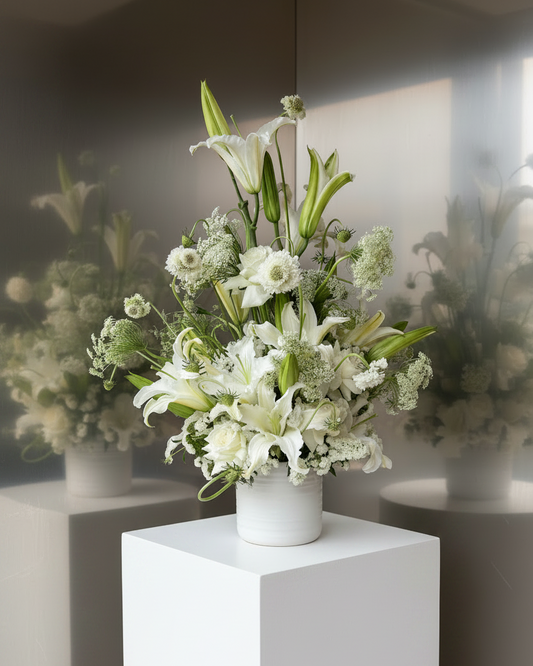 Floral arrangement with lilies in white in a white vase by gathered+styled