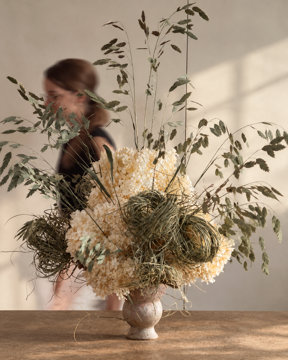 Ecru dried hydrangea and grass centrepiece on a timber table in soft window light