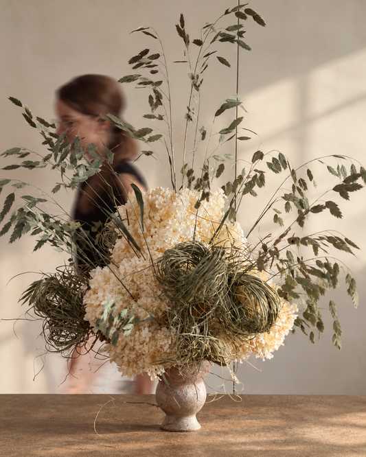 Ecru dried hydrangea and grass centrepiece on a timber table in soft window light